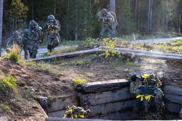 Kaitseväelased maskeerimisvormis liiguvad metsateel edasi ja võtavad sihikule kaevikus oleva vastase sõduri sõjalise õppuse ajal.