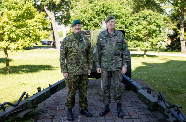 Kaks vormis ohvitseri rohelises digilaigus vormis seisavad õues suurtükiväe relva ees pargialal päikeselisel päeval.