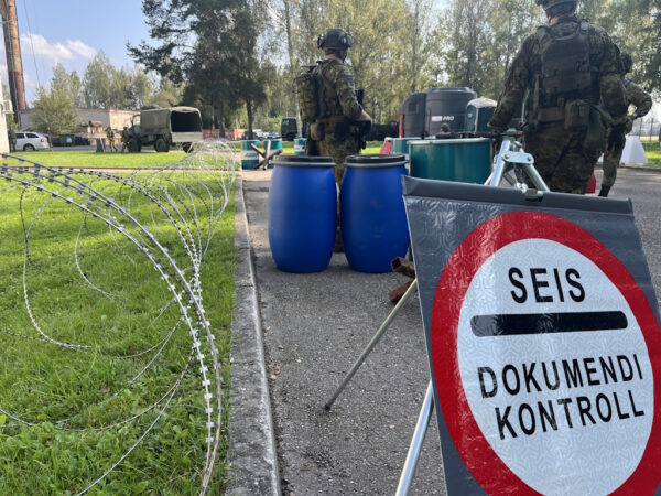 okastraat, kaks kaitseväelastkolmed sinise kanistri kõrval nende taga suur hoiatussilt tekstiga: " SEIS Dokumendi kontroll"