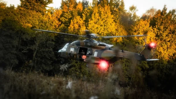 Metsa taustal on maandumas sõjaväehelikopter, sõdur seest näha, aasale