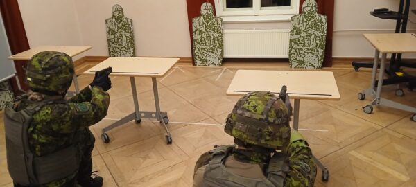 kaks kaitseliitlast sihgivad sihtmärke siseruumis, klassiruum, parkettpõranda ja ratastega laudadega