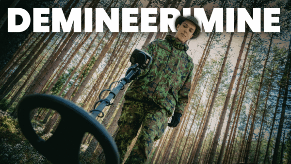 Kujundatud videopilt. Pildil demineerija enda töövahendiga männimetsas. Üleval kiri "demineerimine".